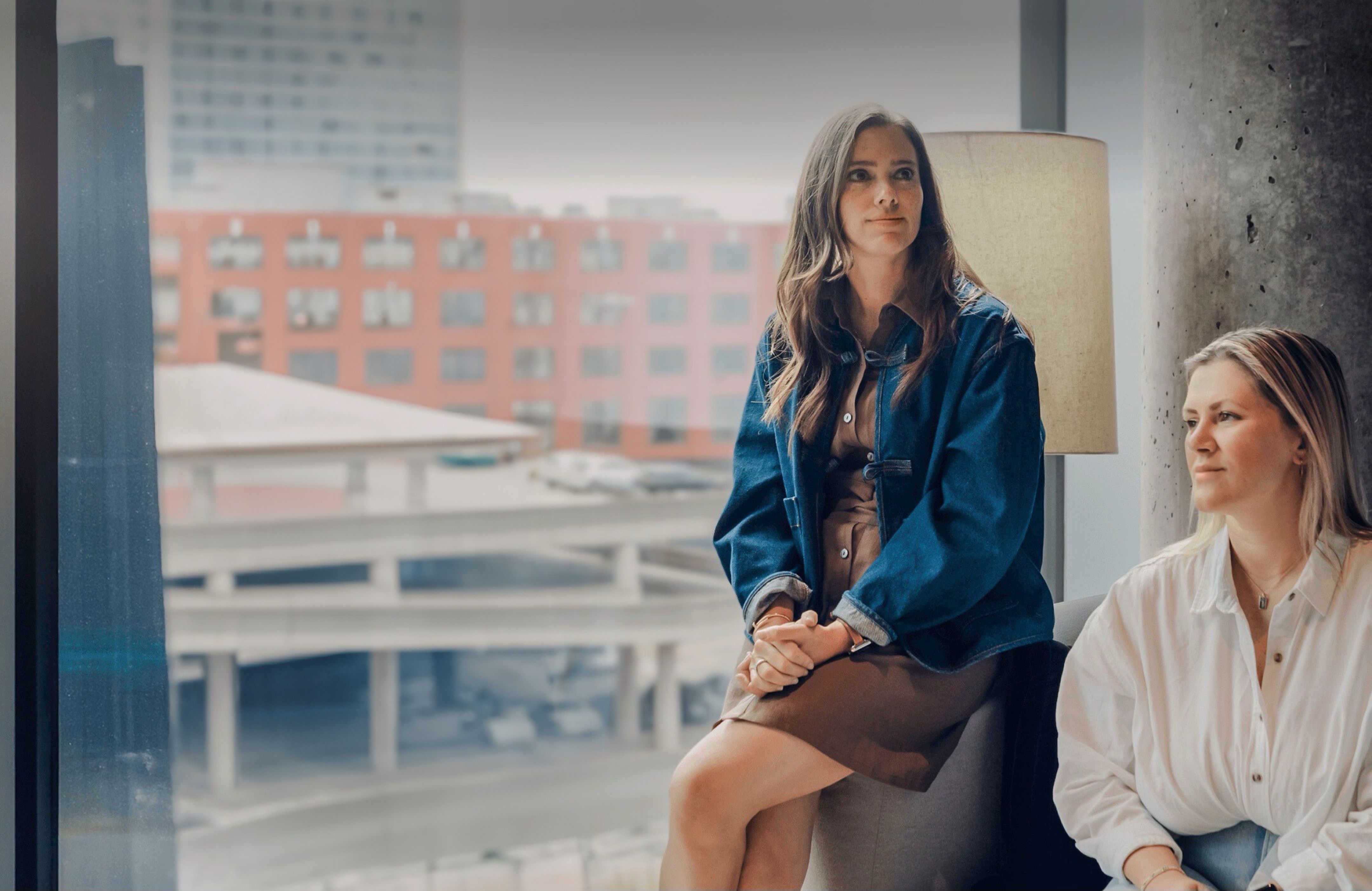 Robyn team at the office sitting by the window smiling with the city in the background