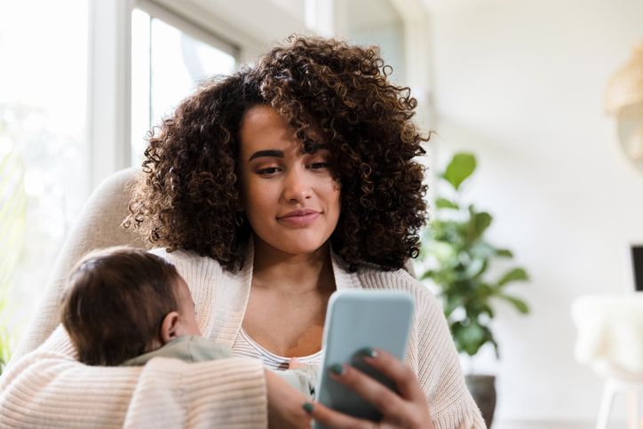 Woman at home holding her child texting
